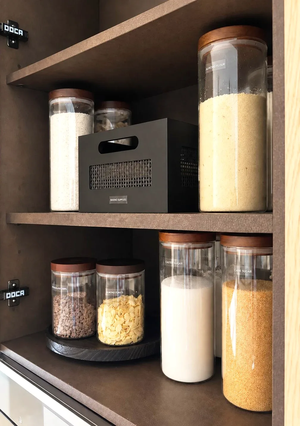 Decanted flour and grains in tall jars on two shelves.