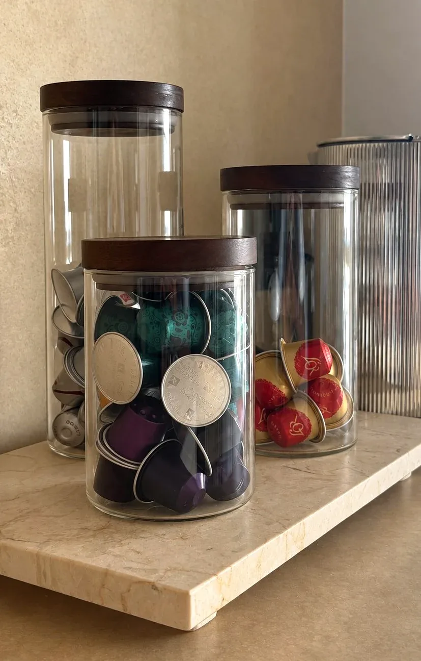 Decanted coffee pods and dried goods in jars on a worktop.