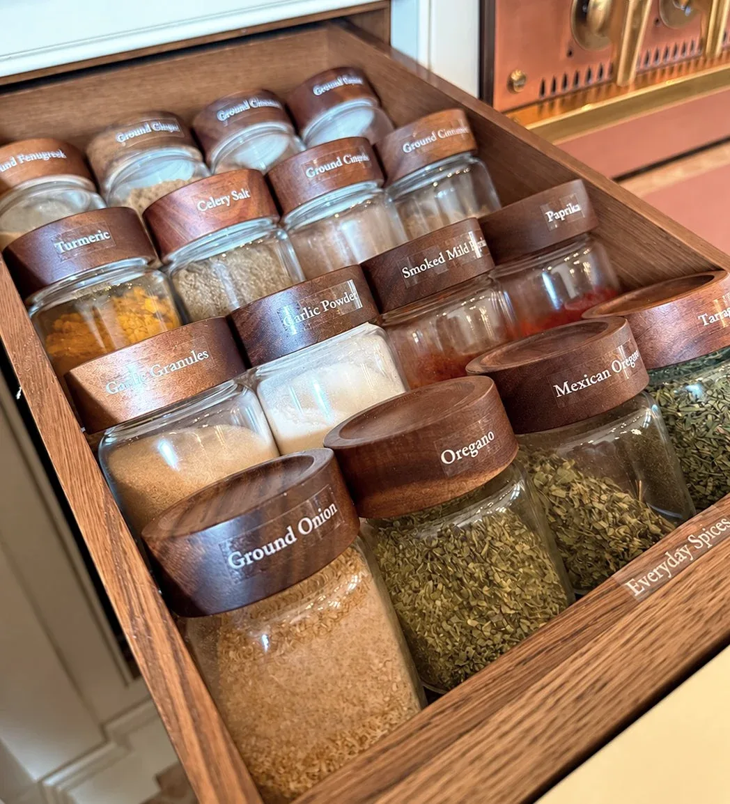 A drawer of labelled spice jars in timber dividers.