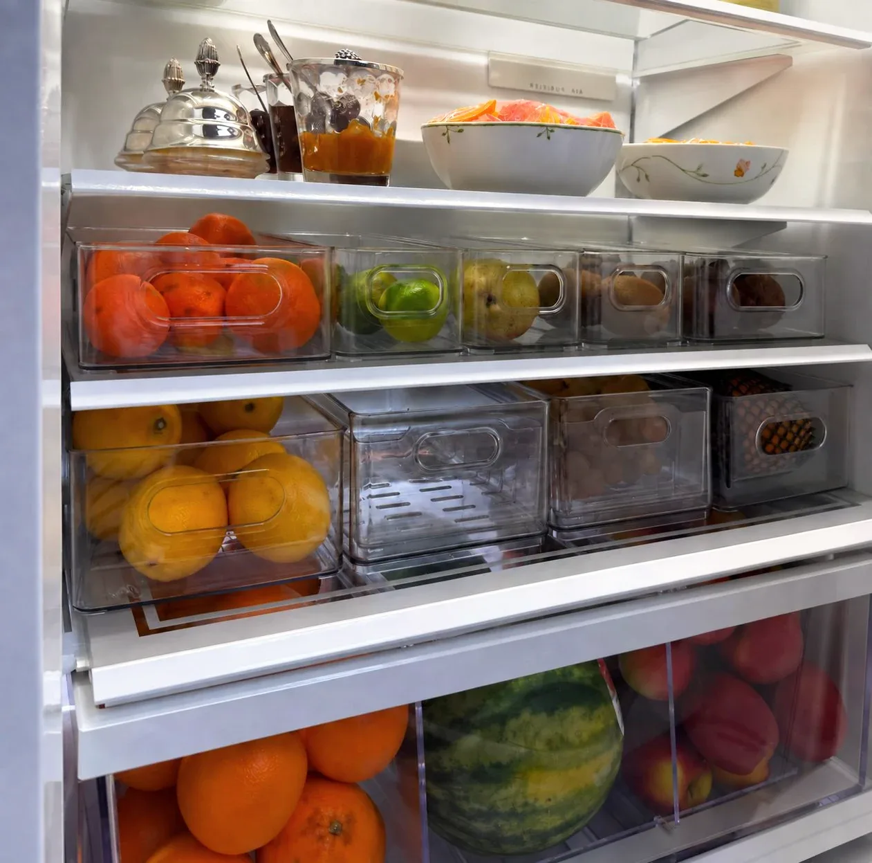 A refrigerator door with condiments in clear containers.