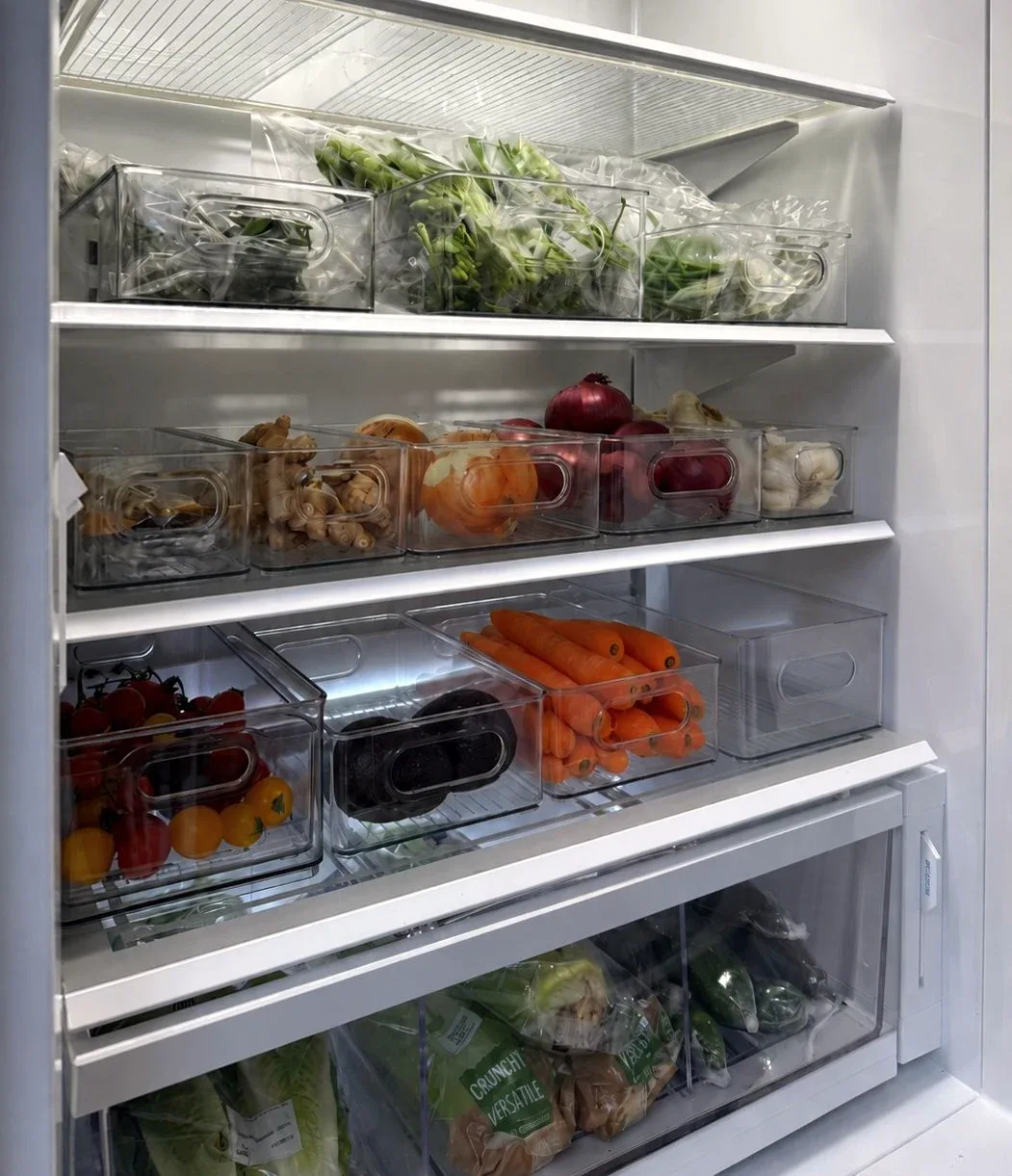 A refrigerator with produce sorted into clear stacking containers.