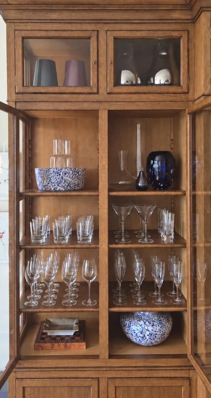 Glassware and decanters behind the glazed doors of a timber cabinet.