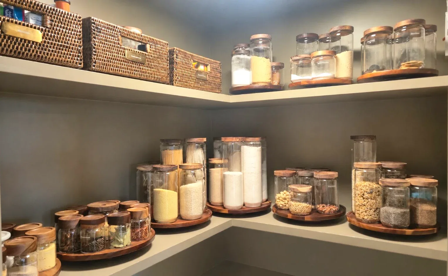 A pantry corner with jars and woven baskets on timber shelves.