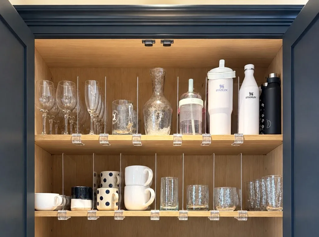Glassware, decanters and cups on the shelves of a painted cabinet.