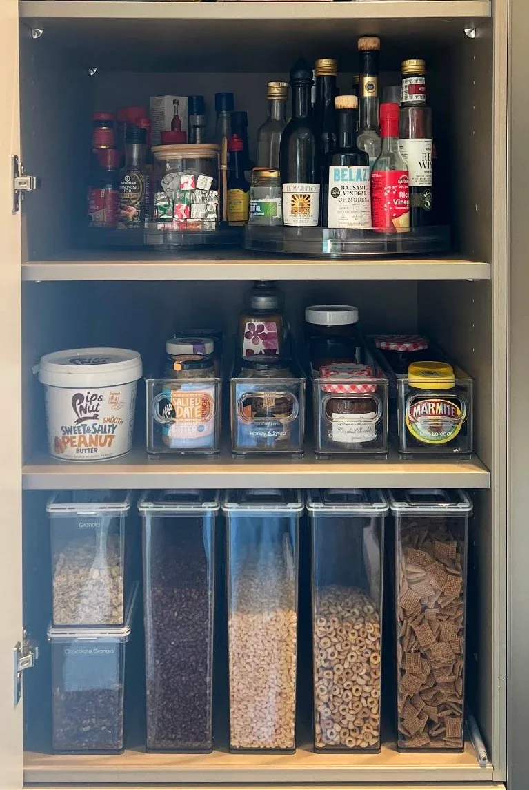Bottles and jars on the shelves of a dark cupboard.