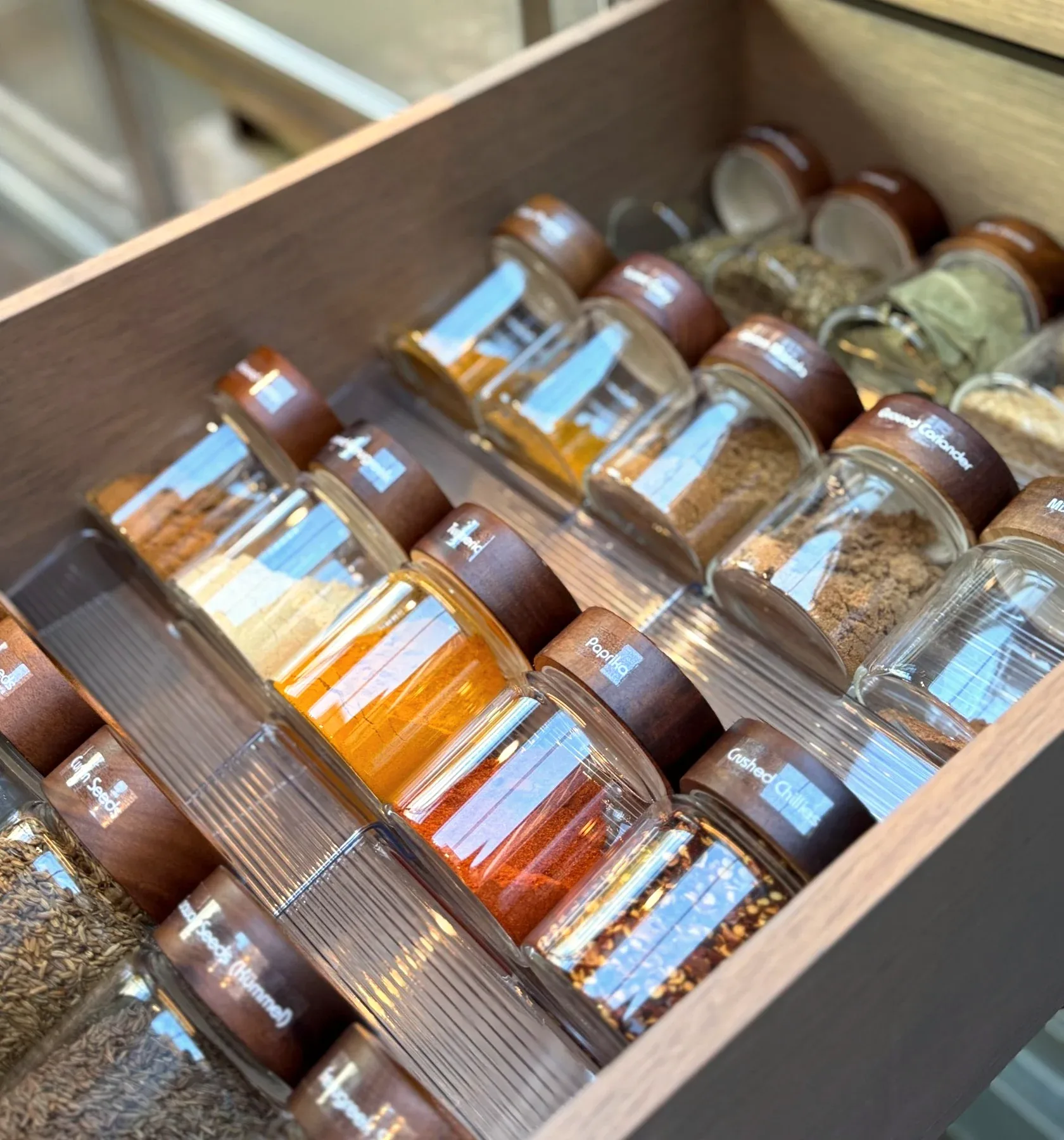 A drawer of spice jars, laid flat and seen from above.