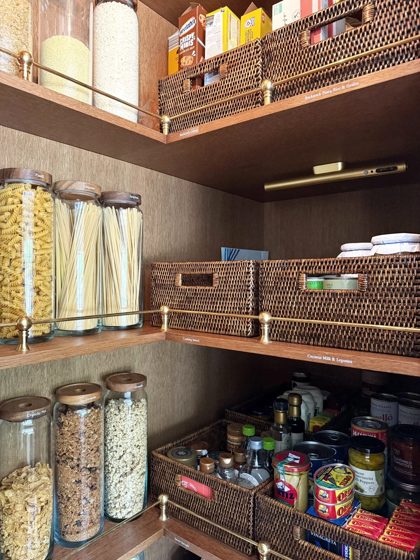 A pantry corner with jars, baskets and packets on timber shelves.