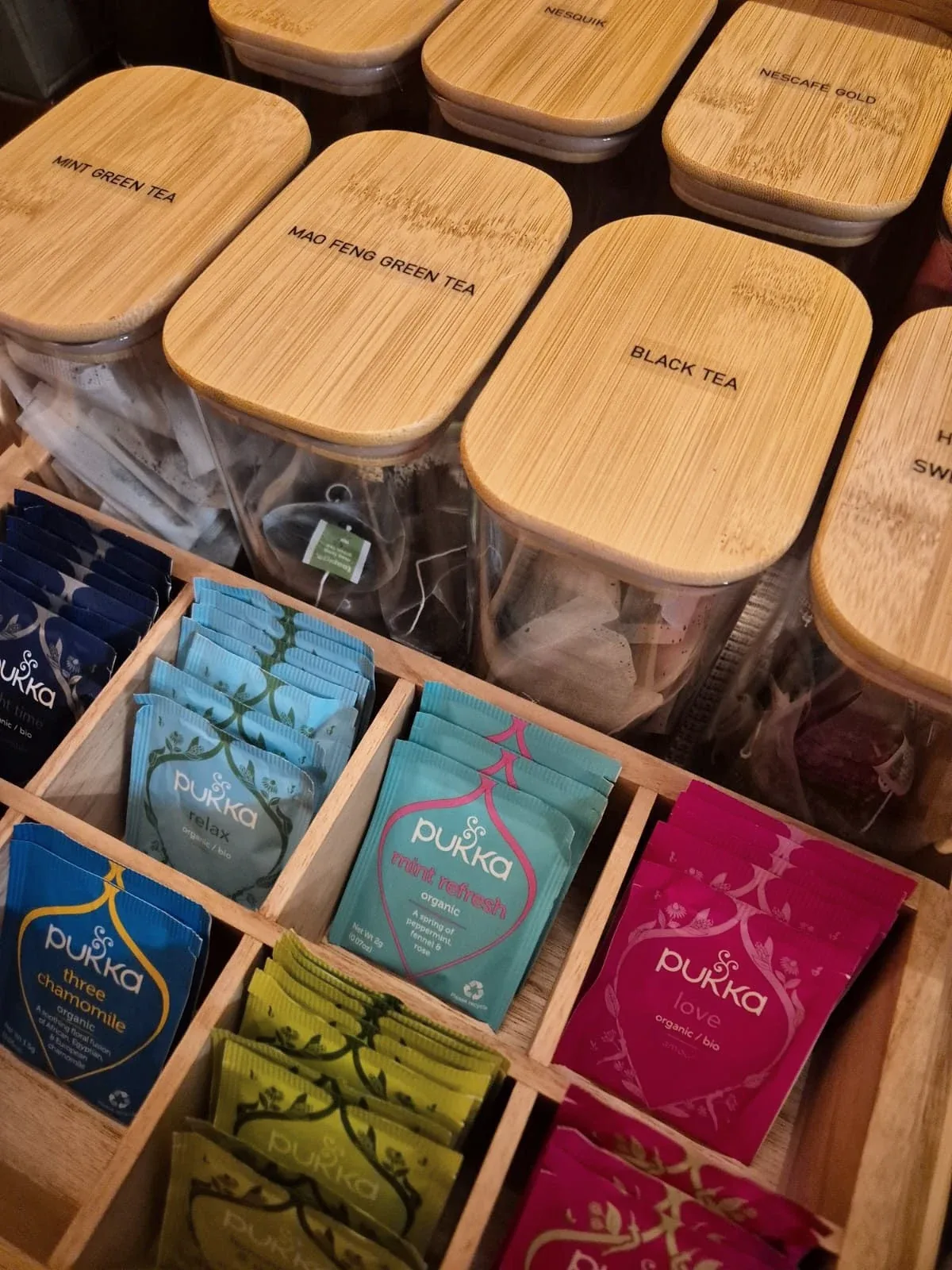 Tea boxes sorted upright in a drawer beside lidded canisters.