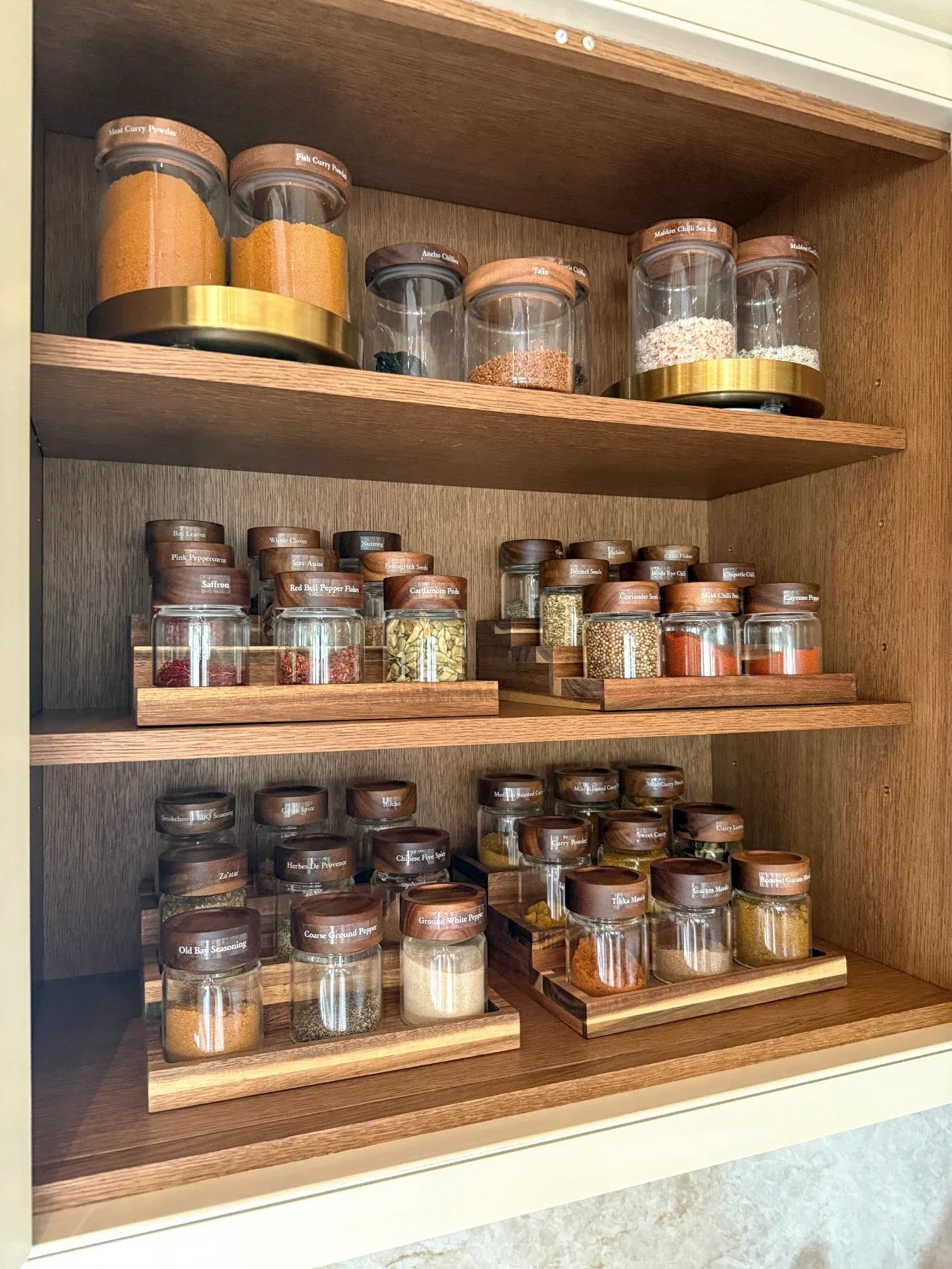 Spice jars on tiered racks above decanted staples.