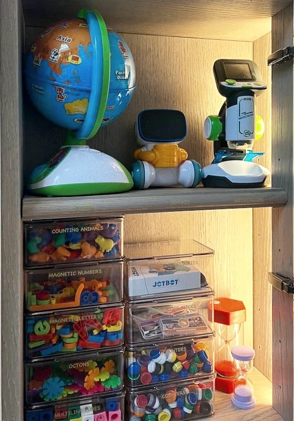 A globe and toys above clear drawers of craft materials.