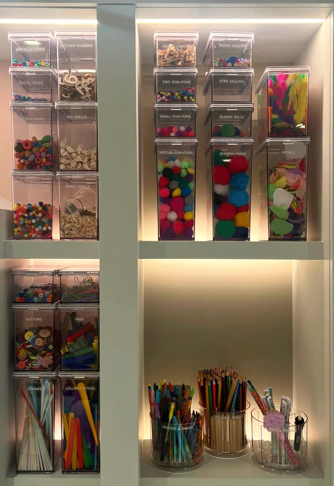 Clear drawers of craft materials beside pots of pencils.