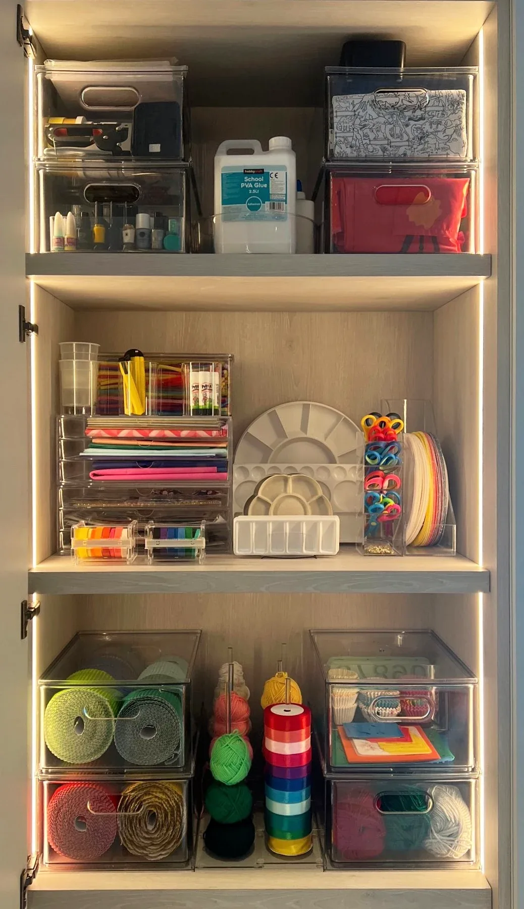 A cabinet of stationery and craft supplies in clear trays.