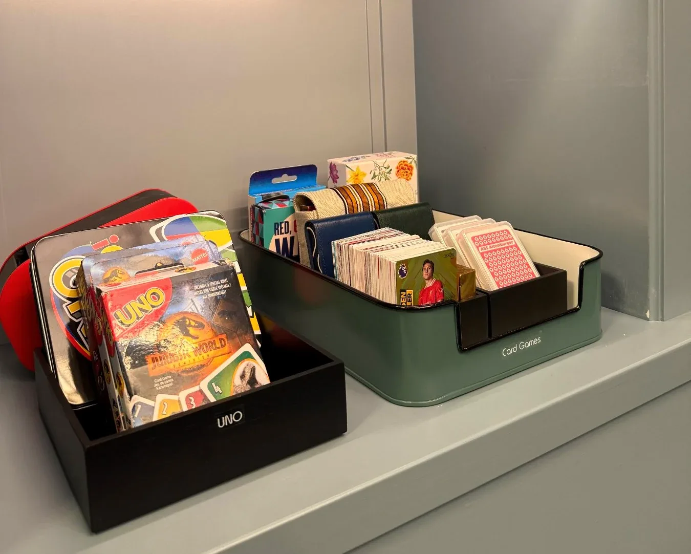 A card game and a caddy of pens on a shelf.