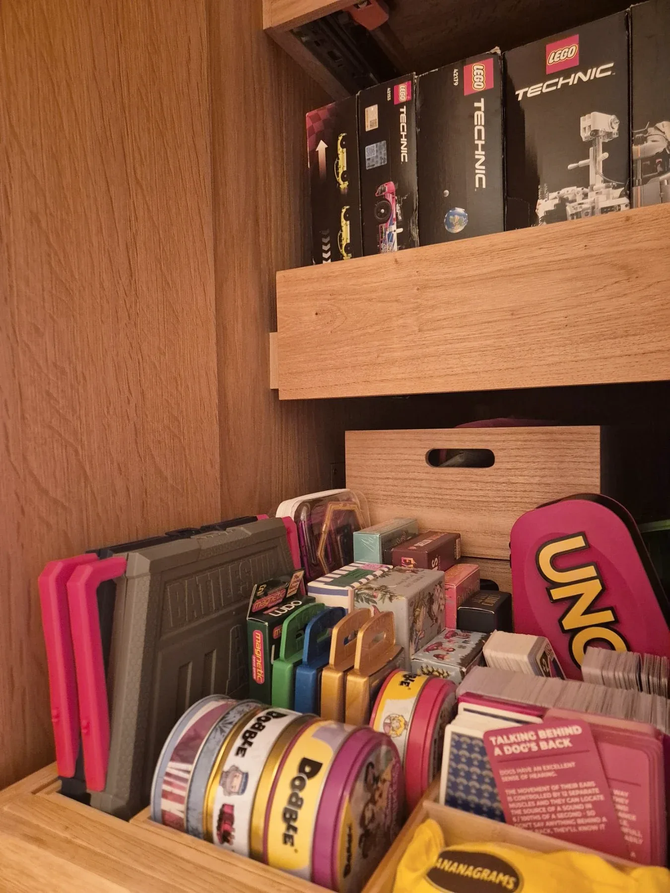 Craft tapes and games stacked in a timber cupboard.