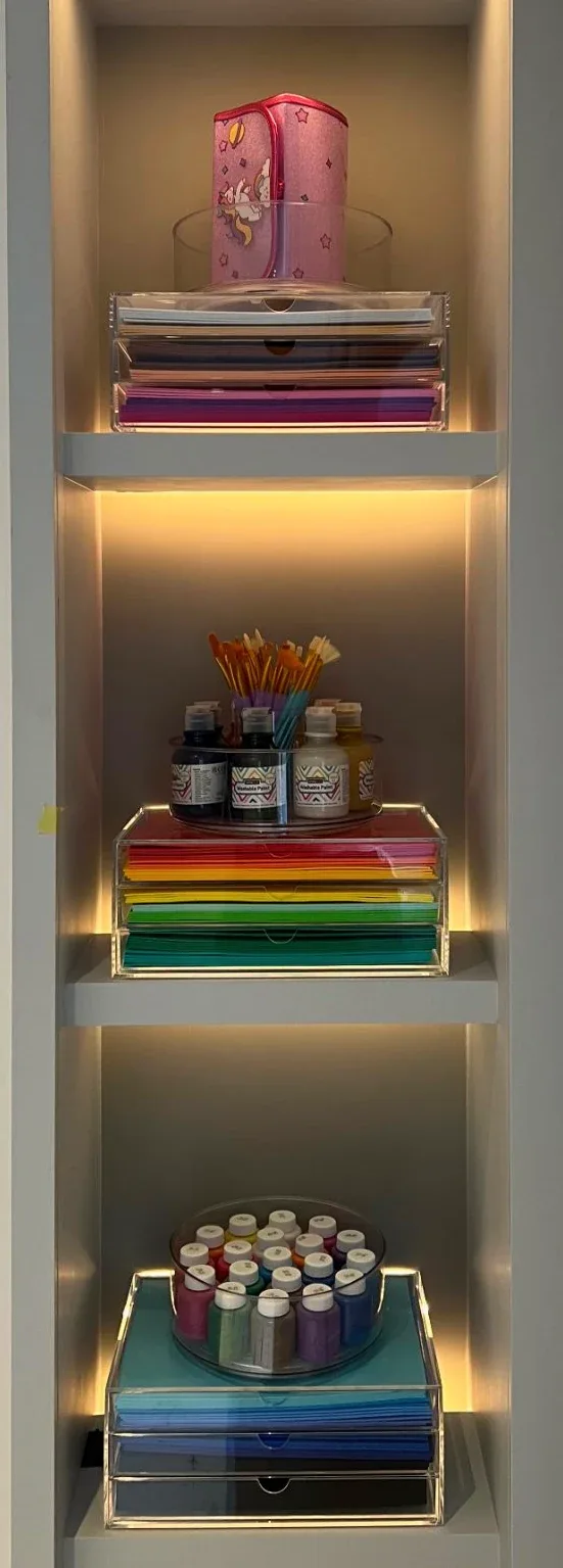A narrow lit niche holding books and small boxes.