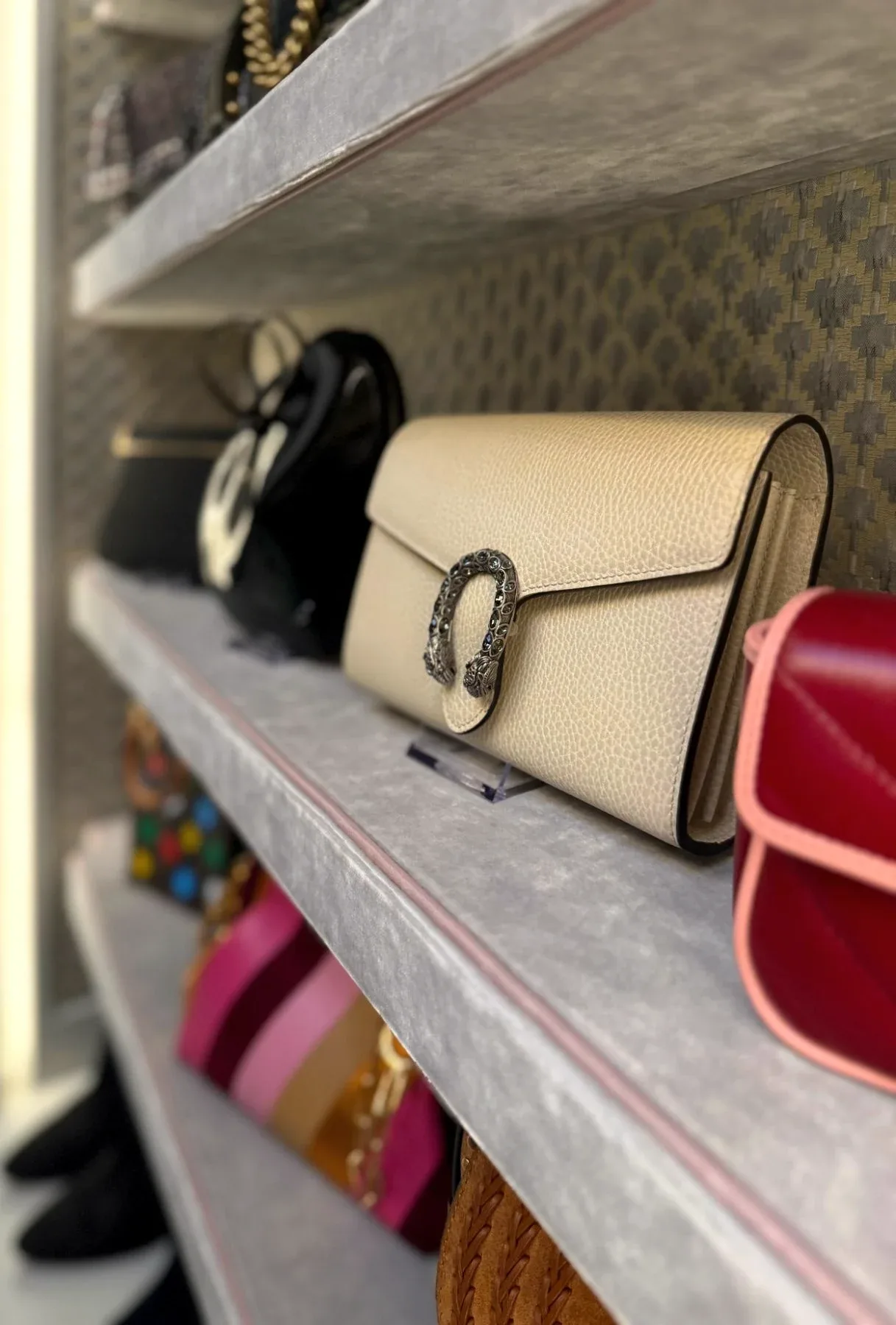 A handbag and a clutch set out on a grey shelf.