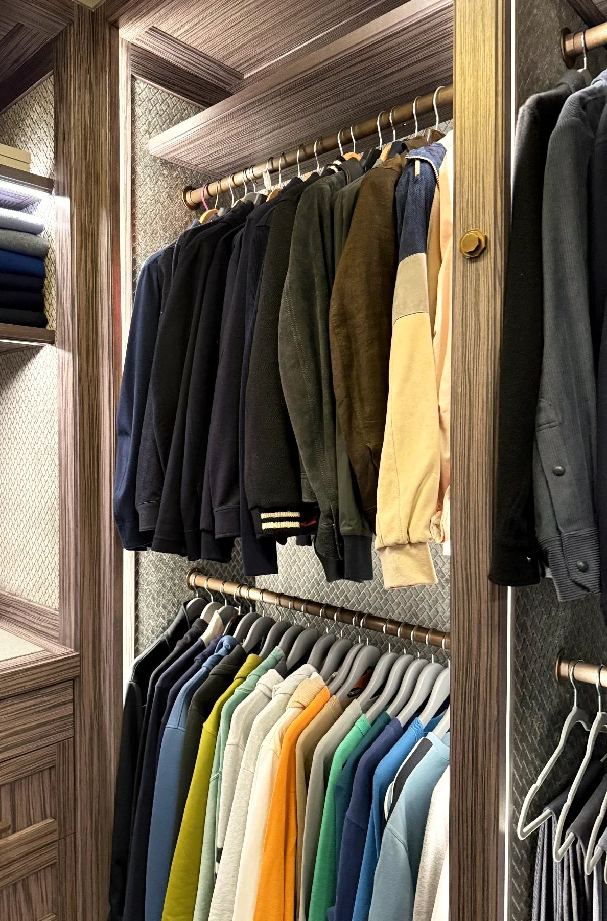 Two rails of hanging clothes in a dressing room.