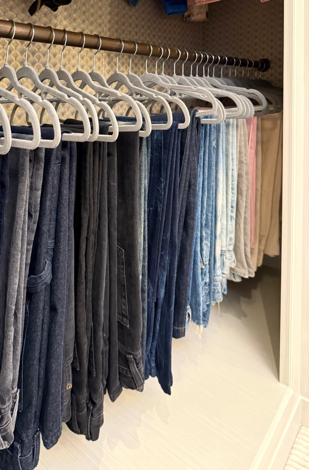 Jeans hanging in a row on matching hangers.