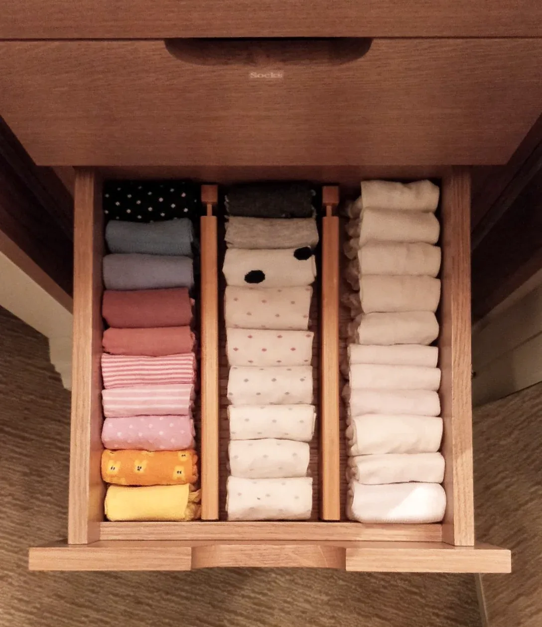 A drawer of folded babywear sorted into compartments.