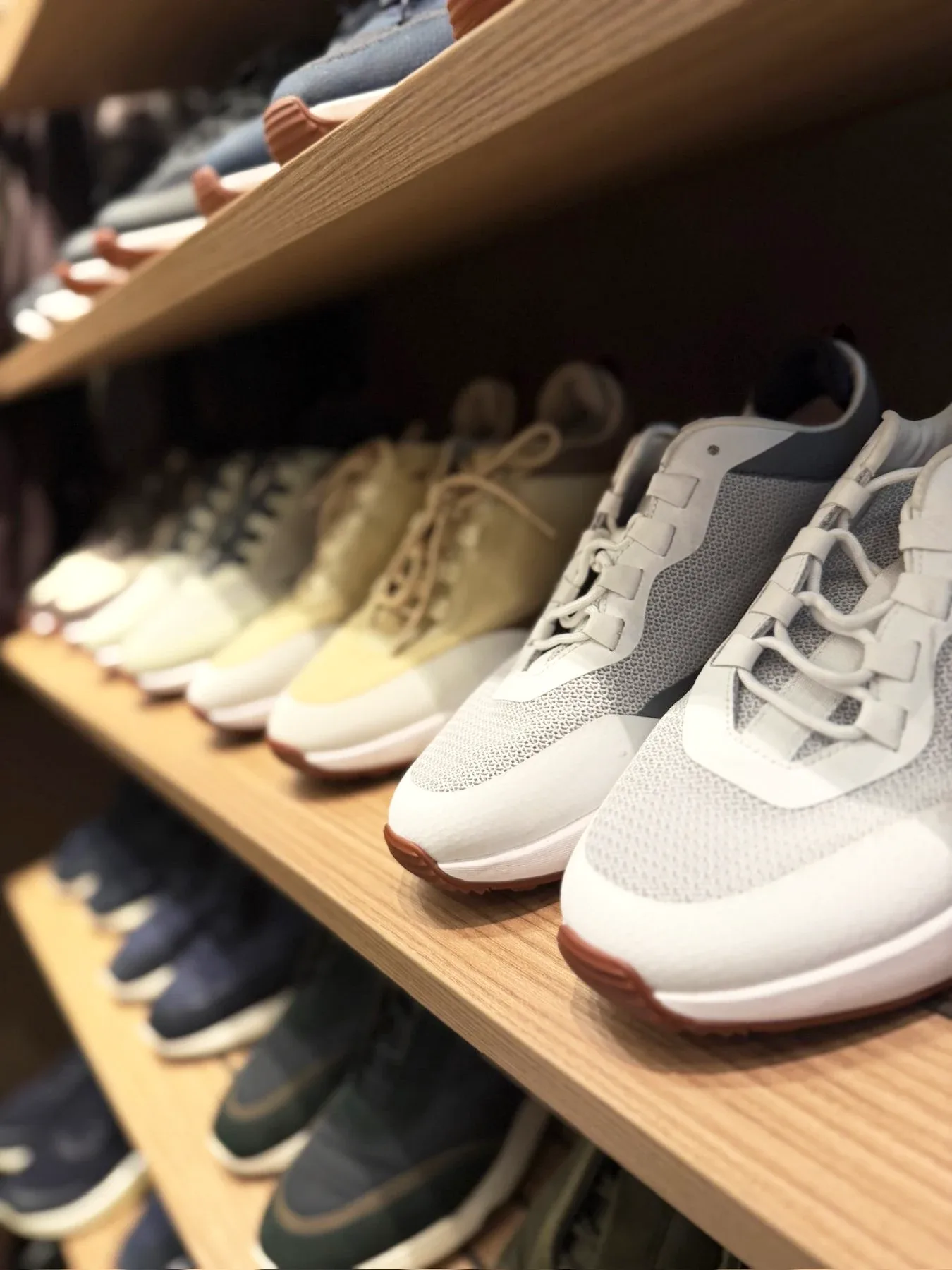 Trainers and shoes lined along a timber shelf.