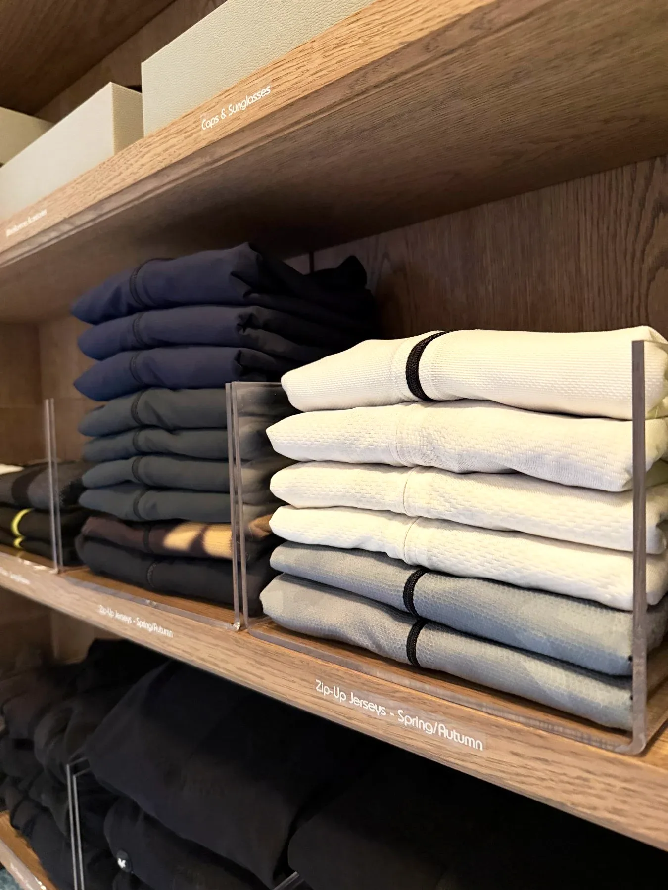 Folded knitwear and denim stacked on timber shelves.