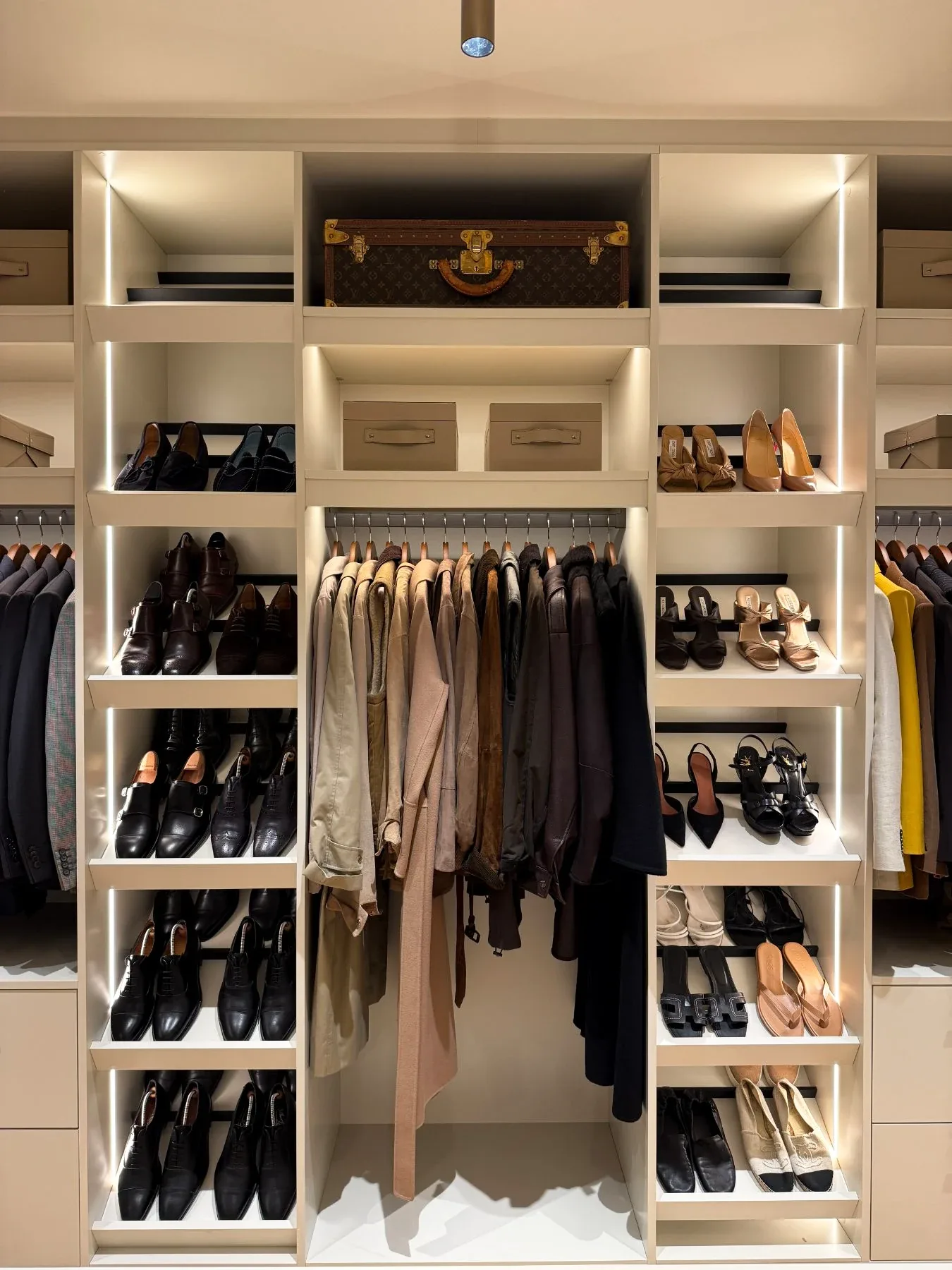 A dressing room with a central hanging bay, shoe shelves either side and storage boxes above.