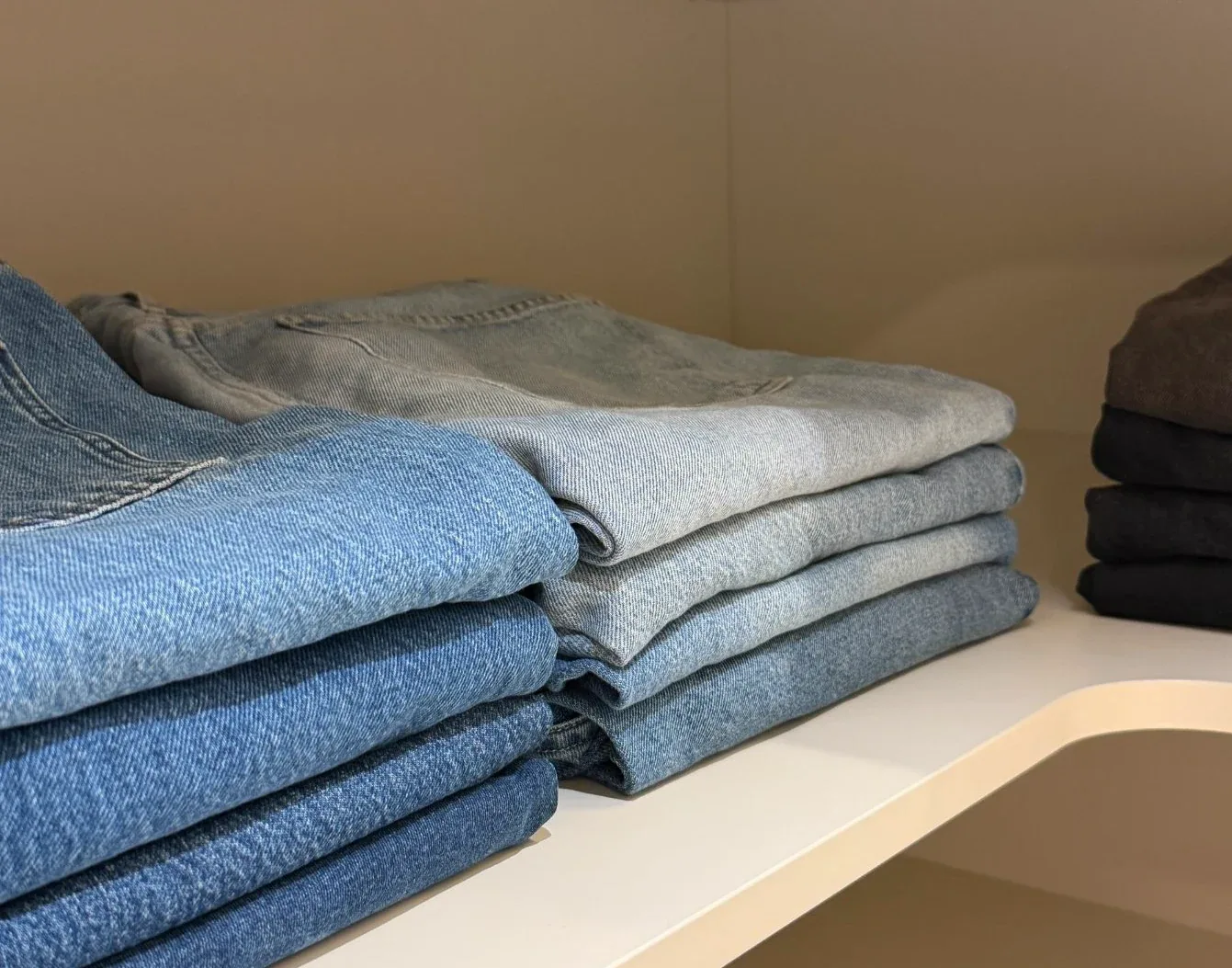 Folded jeans stacked on a wardrobe shelf.