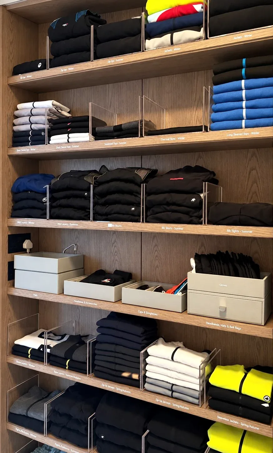 Folded shirts and accessories on open shelves with clear drawer inserts.