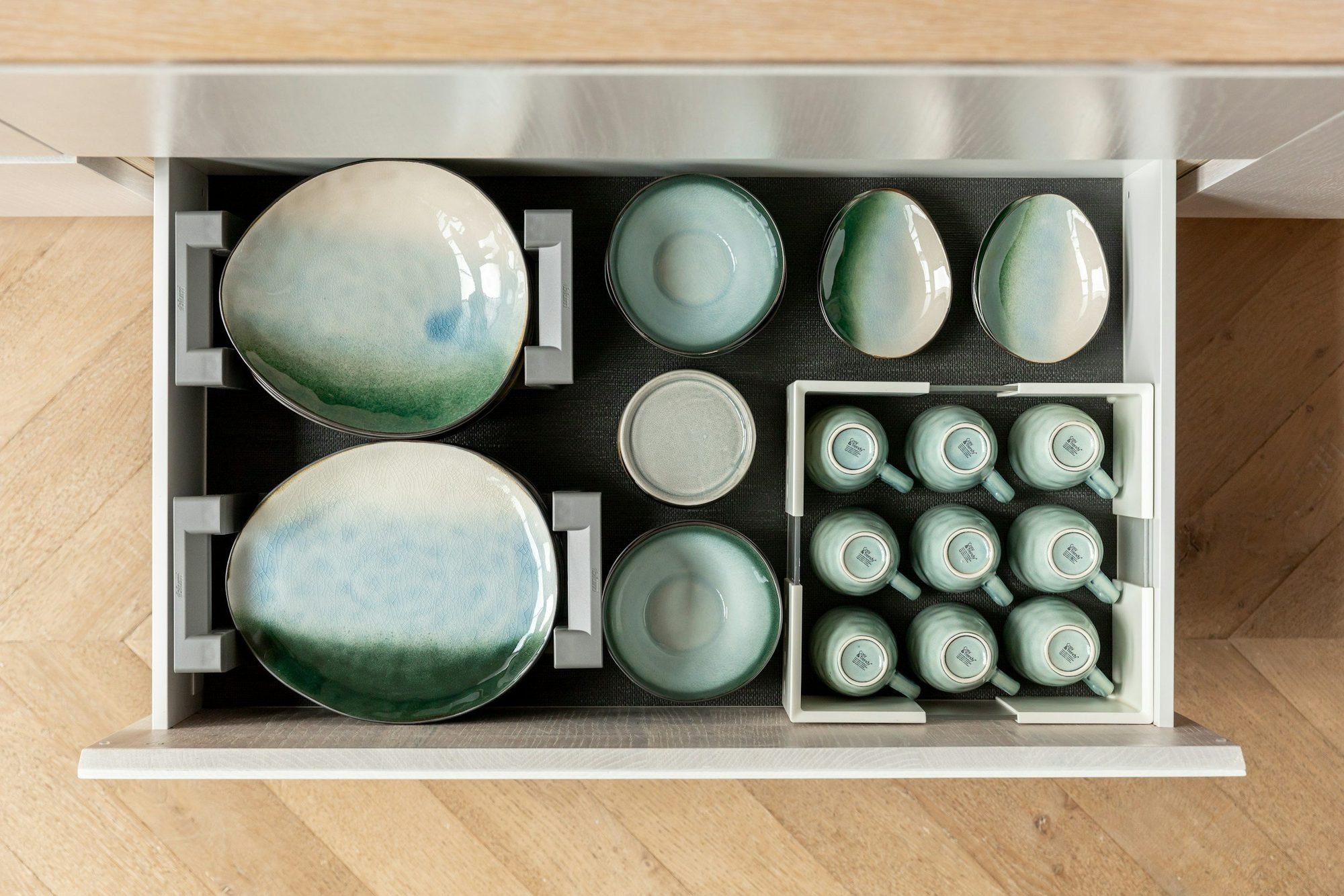 Plates and cups set into a deep kitchen drawer.