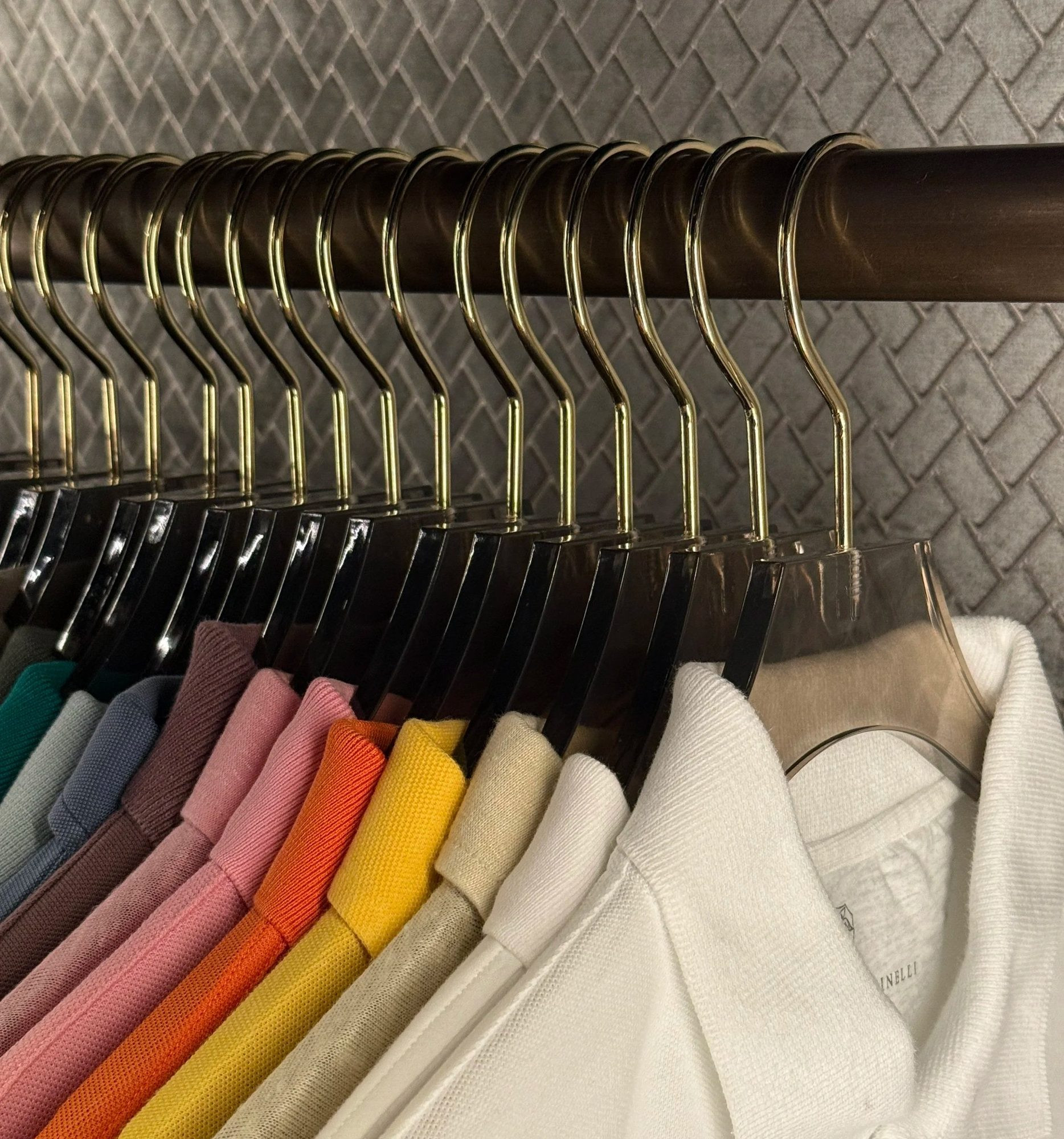 Clothes hung by colour on matching hangers.