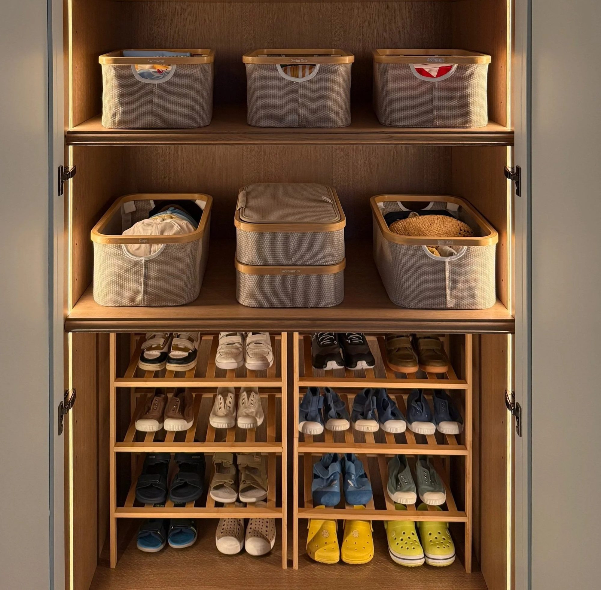 Lidded baskets on cupboard shelves above shoes arranged in pairs.