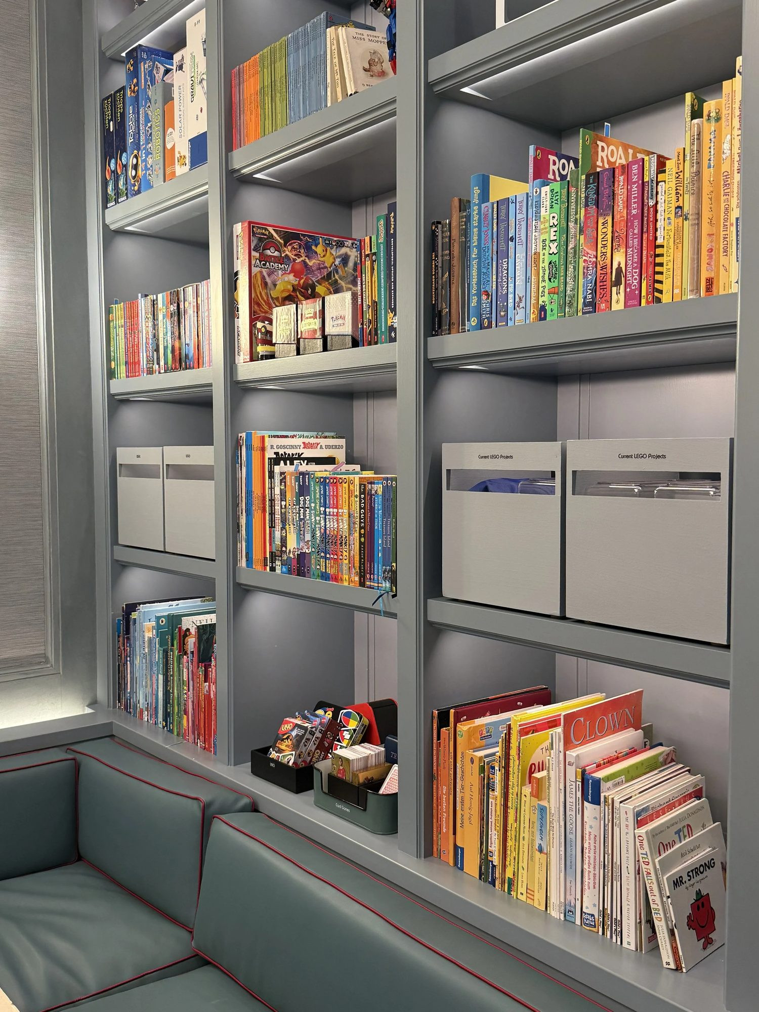 Shelves of children's books and storage boxes in a playroom.