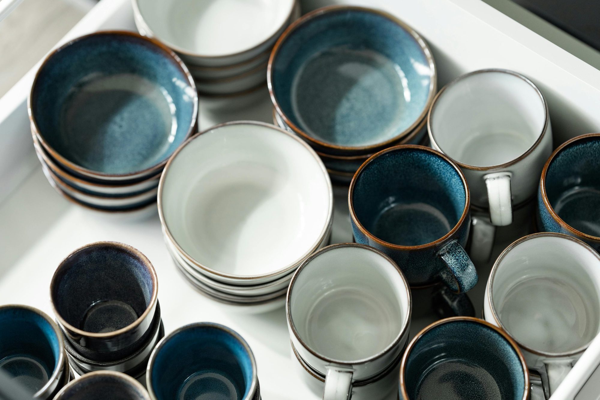 Bowls and cups grouped in a kitchen drawer.