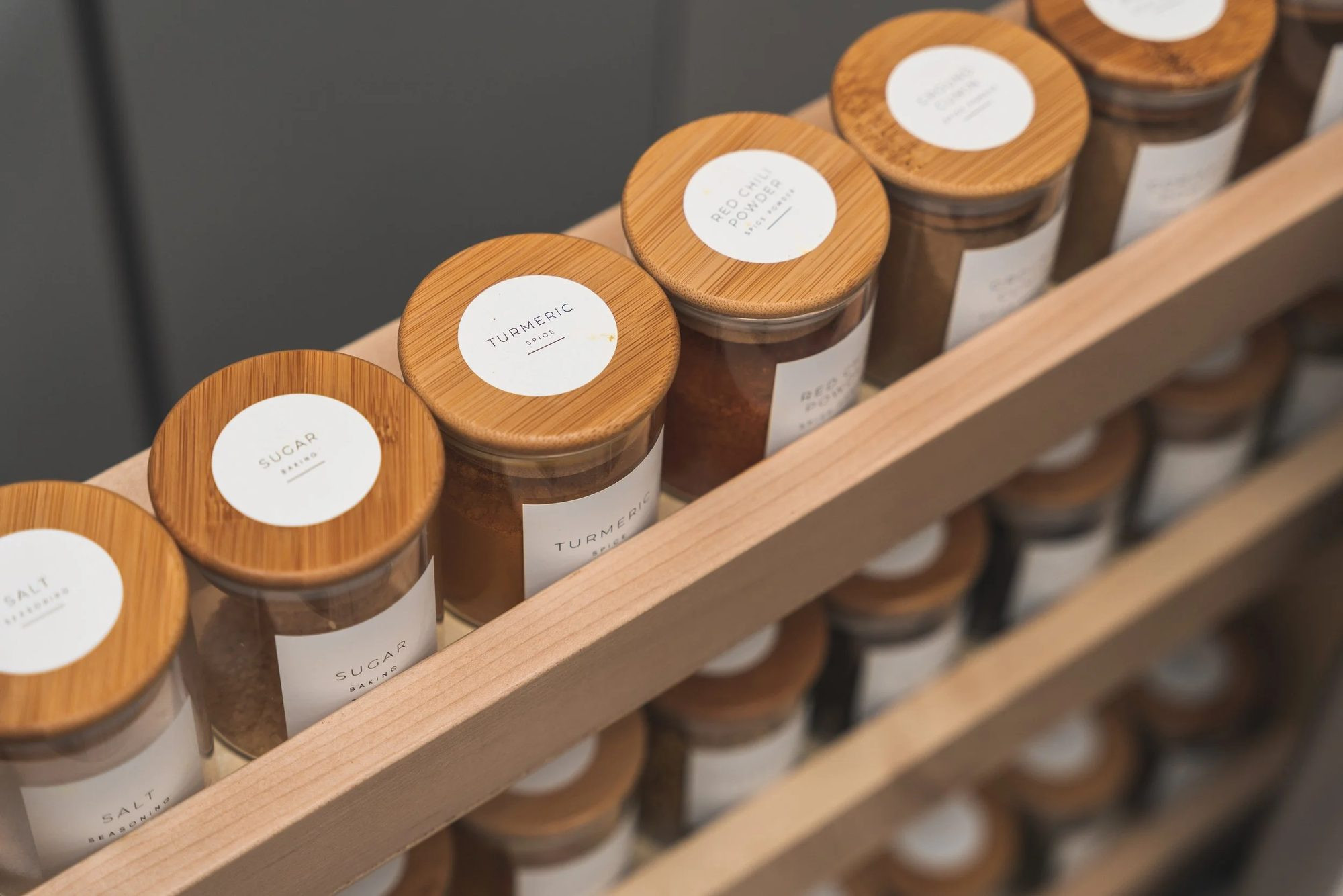 Labelled jars on a wooden spice rack.