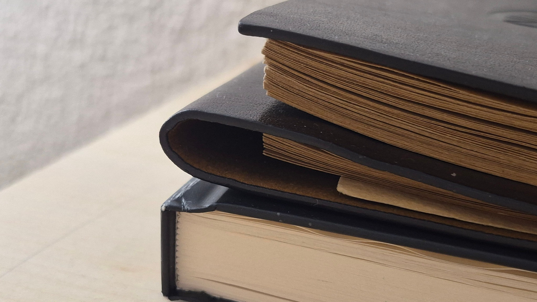 Leather-bound albums and books stacked on a table.